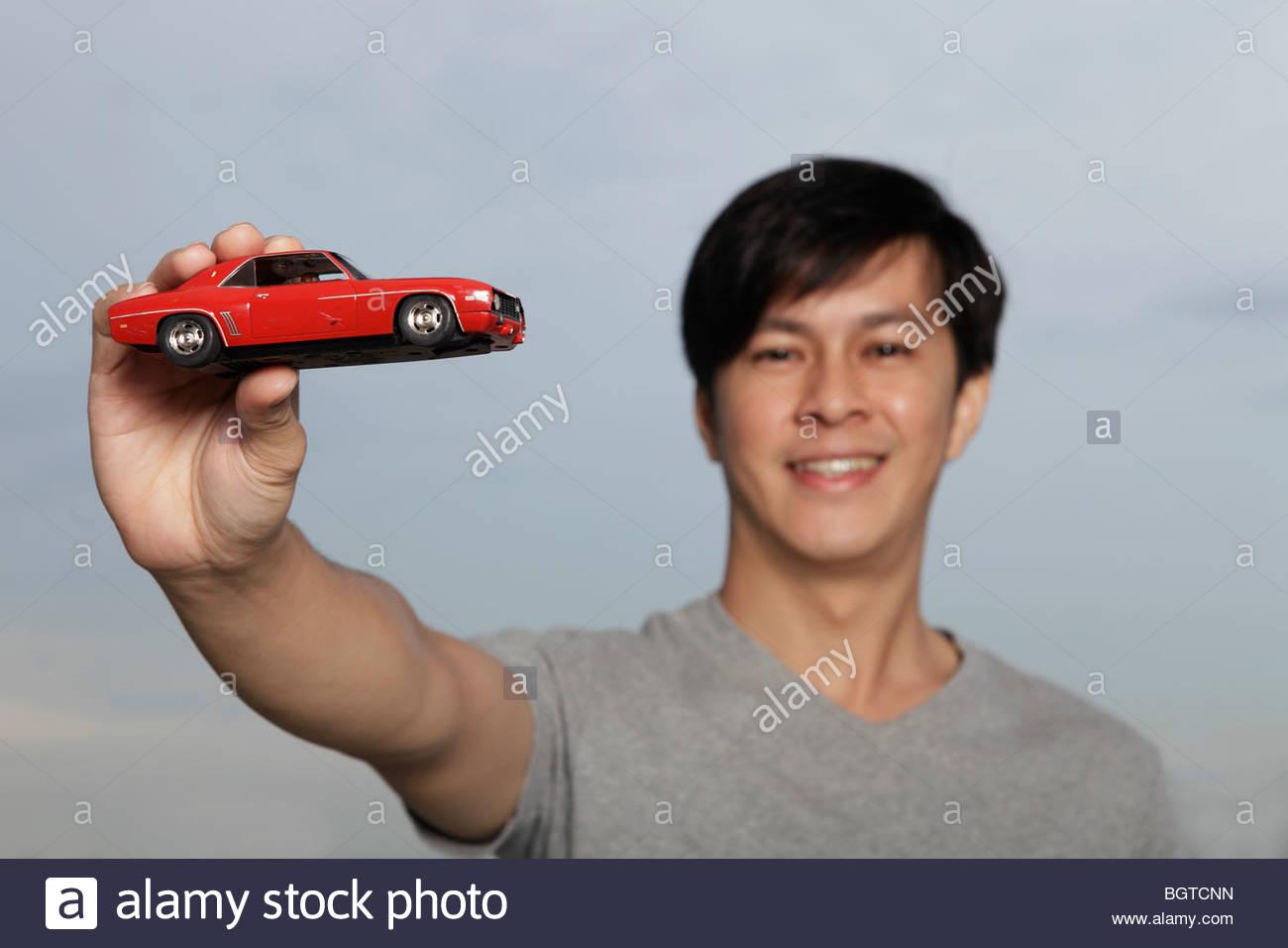 young-man-holding-up-red-toy-car-BGTCNN.jpg